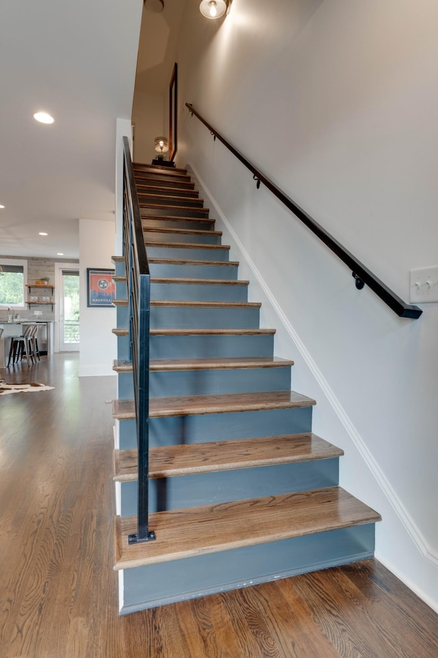 stairs with wood finished floors, recessed lighting, and baseboards