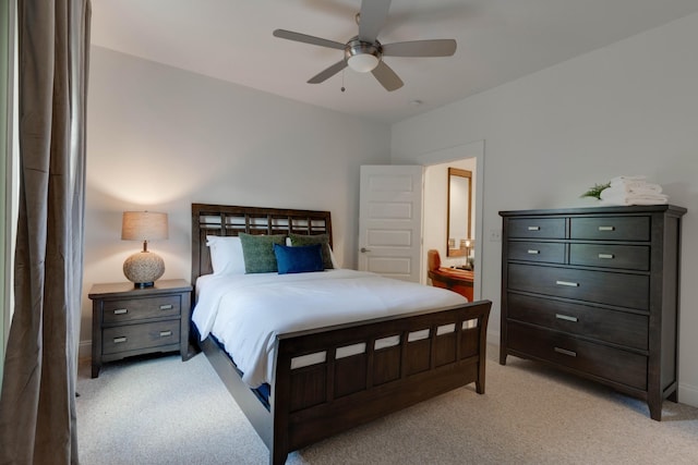 bedroom with light colored carpet, ensuite bath, a ceiling fan, and baseboards