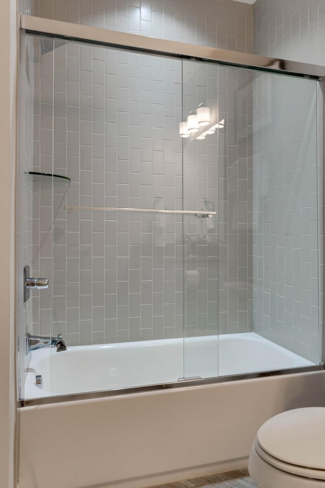 full bath featuring combined bath / shower with glass door and toilet