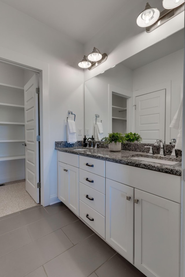 bathroom featuring double vanity, a walk in closet, tile patterned flooring, and baseboards