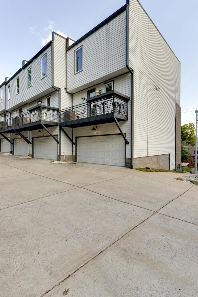 rear view of property with a garage, driveway, and a balcony