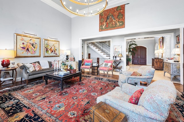 living room featuring crown molding, a chandelier, wood finished floors, stairs, and arched walkways
