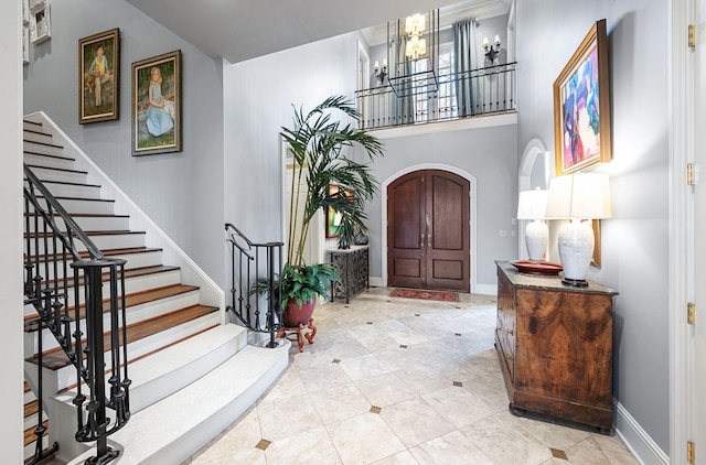 entryway featuring stairs, arched walkways, a chandelier, baseboards, and tile patterned flooring