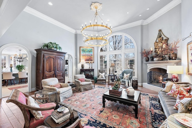 living area with a chandelier, a lit fireplace, arched walkways, wood finished floors, and a high ceiling