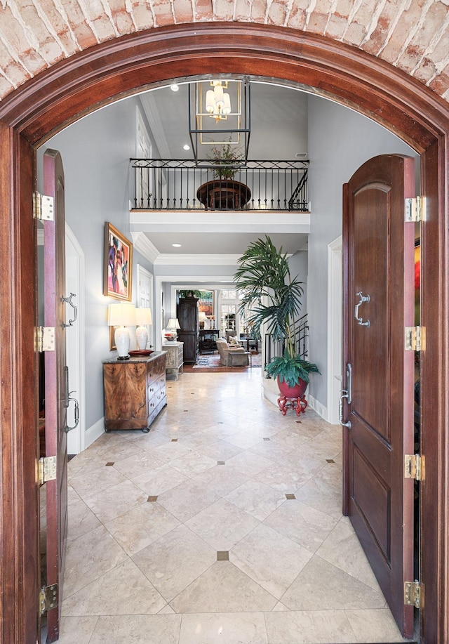 foyer entrance with arched walkways, a towering ceiling, a chandelier, baseboards, and recessed lighting