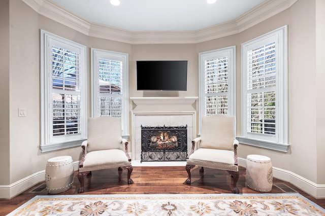 sitting room featuring healthy amount of natural light, baseboards, a fireplace, wood finished floors, and ornamental molding