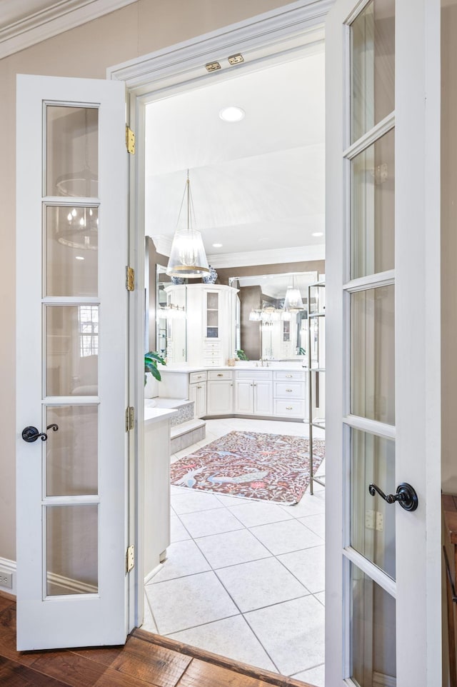 tiled entrance foyer with a chandelier and crown molding