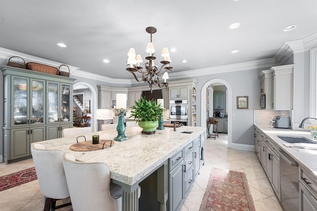kitchen featuring arched walkways, a chandelier, a sink, a kitchen island, and crown molding