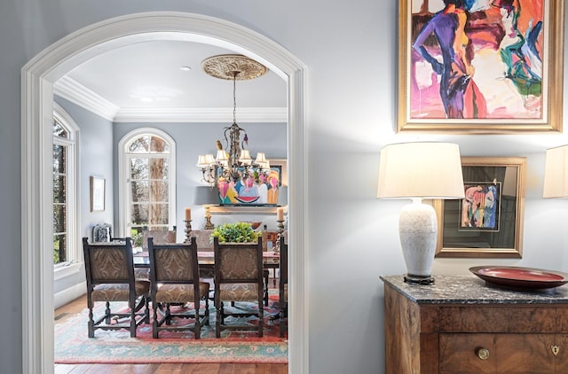 dining area featuring a chandelier, crown molding, arched walkways, and wood finished floors