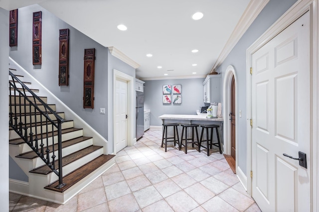 entryway with crown molding, stairway, recessed lighting, baseboards, and arched walkways