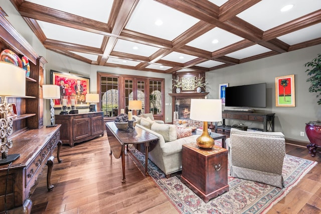 living area with light wood-type flooring, coffered ceiling, beam ceiling, baseboards, and a lit fireplace