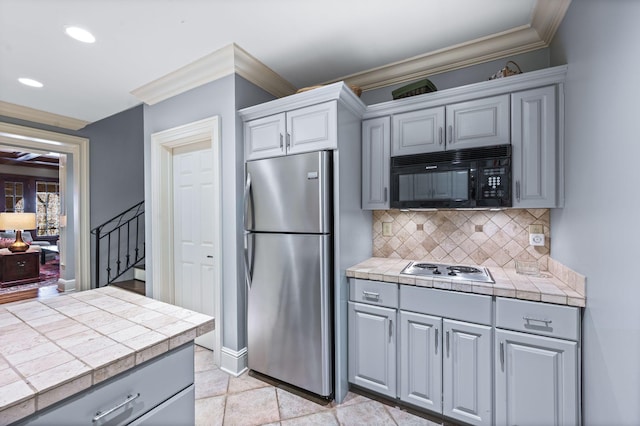 kitchen featuring stainless steel appliances, gray cabinets, tile counters, ornamental molding, and recessed lighting