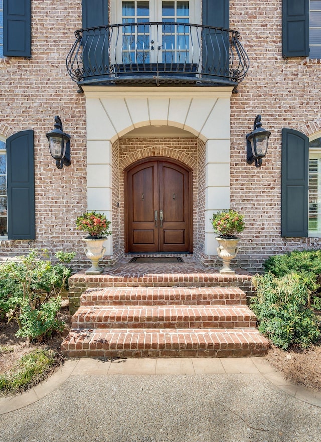 property entrance featuring a balcony and brick siding