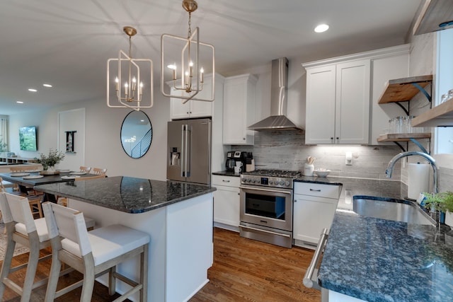 kitchen featuring appliances with stainless steel finishes, wall chimney range hood, a sink, a center island, and decorative backsplash