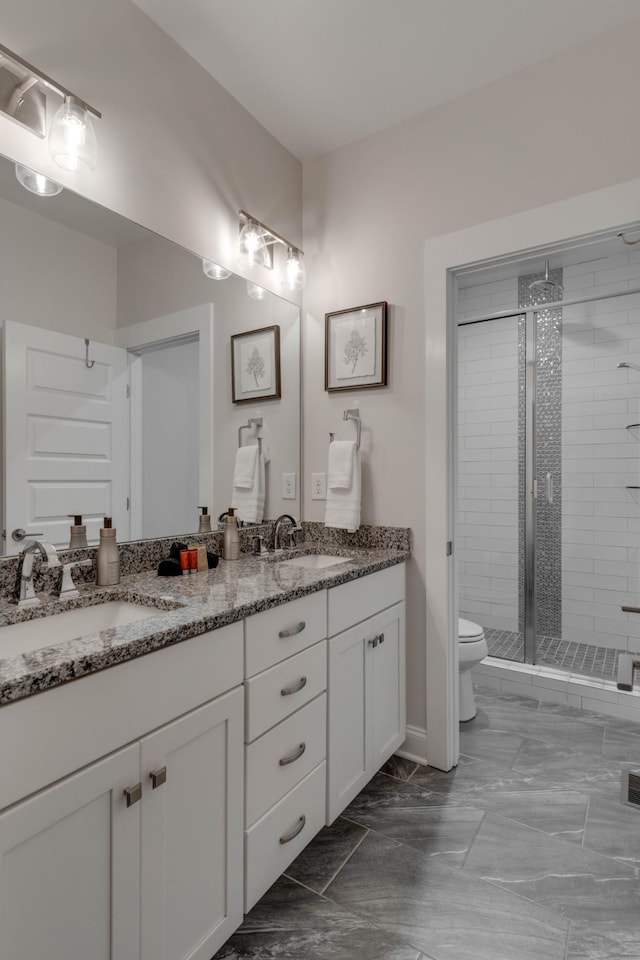 bathroom with a shower stall, toilet, double vanity, baseboards, and marble finish floors