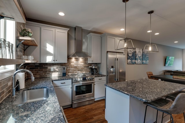 kitchen with high end appliances, wall chimney exhaust hood, a sink, open shelves, and tasteful backsplash