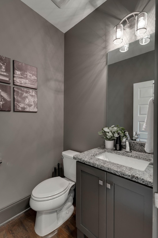 half bath featuring toilet, wood finished floors, and vanity