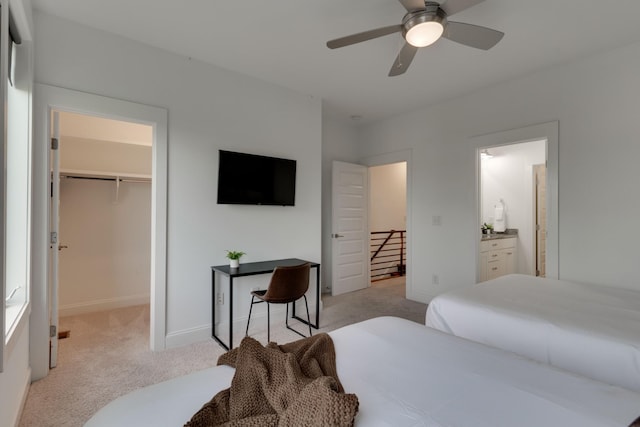 bedroom with light colored carpet, a walk in closet, a ceiling fan, and baseboards