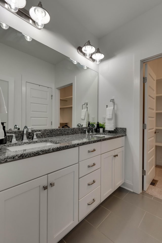 bathroom with double vanity, a walk in closet, and tile patterned floors
