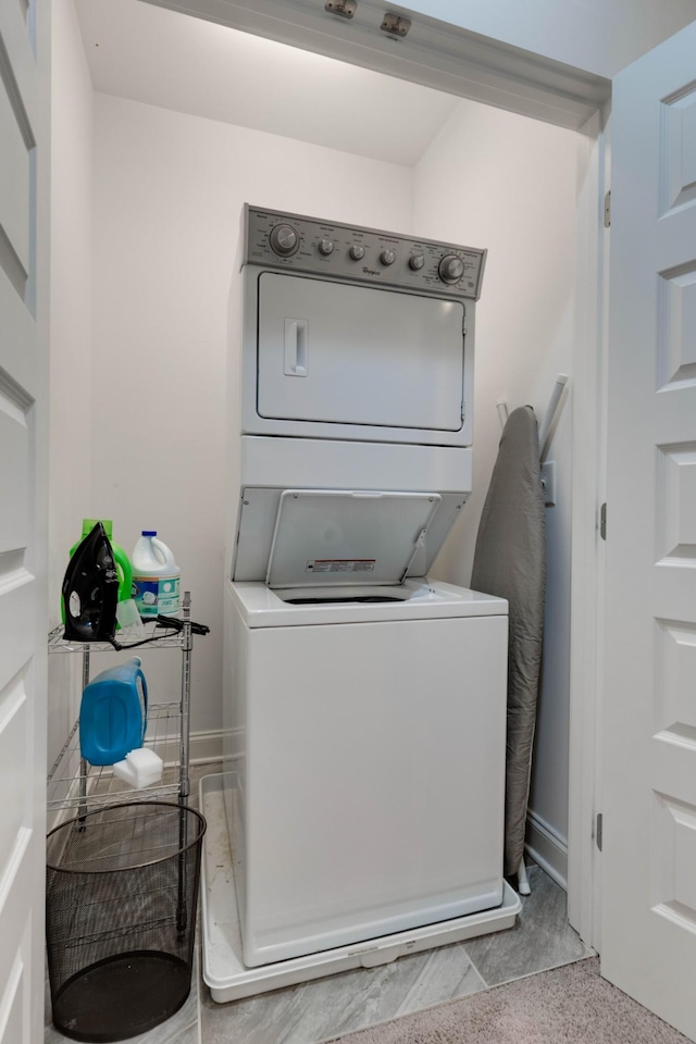 laundry area featuring stacked washer and clothes dryer and baseboards