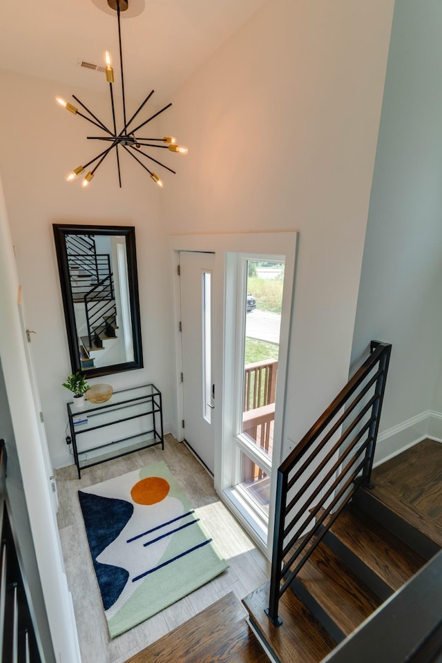 foyer entrance with a chandelier, wood finished floors, baseboards, and a high ceiling
