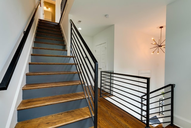 stairs featuring a chandelier, baseboards, and wood finished floors