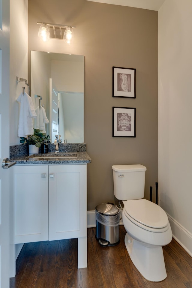 bathroom with baseboards, wood finished floors, toilet, and vanity