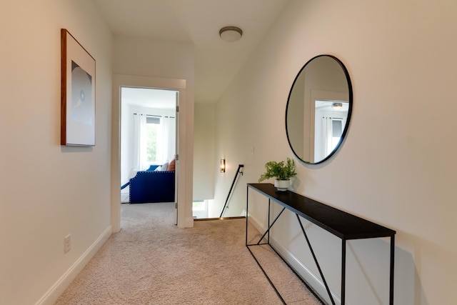 hallway featuring an upstairs landing, carpet flooring, and baseboards