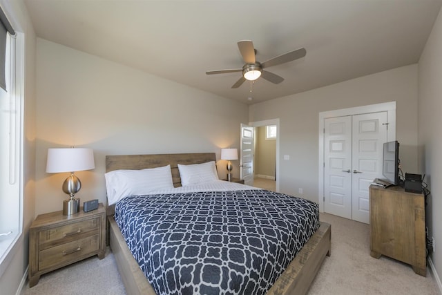 bedroom with light colored carpet, a closet, ceiling fan, and baseboards