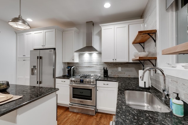 kitchen featuring premium appliances, wall chimney range hood, open shelves, a sink, and white cabinets