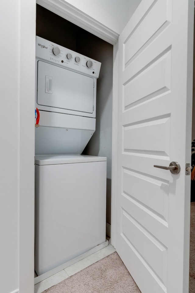 laundry room with stacked washer and clothes dryer and carpet