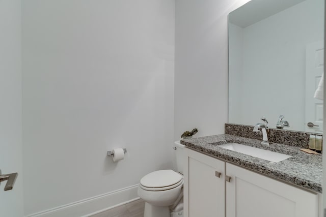 half bathroom featuring toilet, baseboards, vanity, and wood finished floors