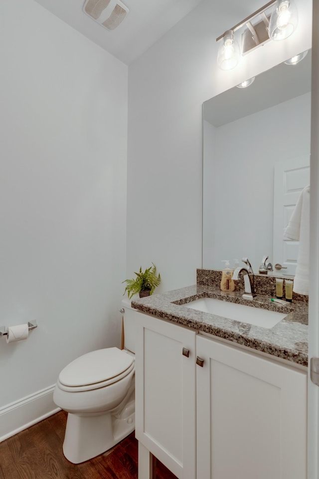 bathroom featuring wood finished floors, toilet, and vanity