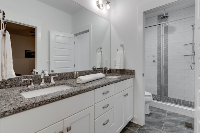 bathroom with a stall shower, double vanity, and toilet