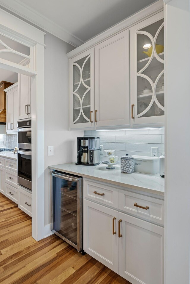 7480 Horn Tavern Rd, Fairview, TN 37062 - bar area with wine cooler, backsplash, light wood-style floors, stainless steel double oven, and crown molding