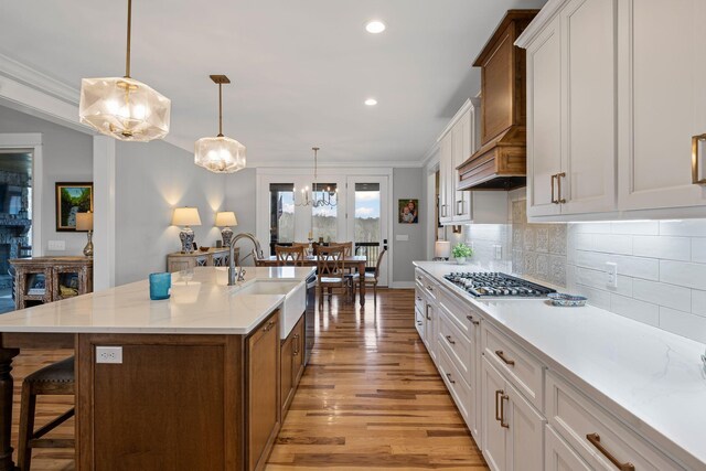 7480 Horn Tavern Rd, Fairview, TN 37062 - kitchen with stainless steel gas stovetop, a sink, light wood-style floors, decorative backsplash, and a kitchen breakfast bar