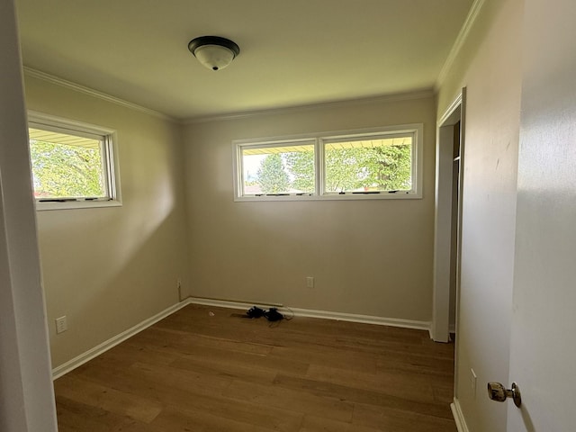 unfurnished room featuring healthy amount of natural light, crown molding, wood finished floors, and baseboards