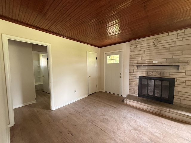 unfurnished living room with baseboards, a fireplace, wood finished floors, wooden ceiling, and crown molding