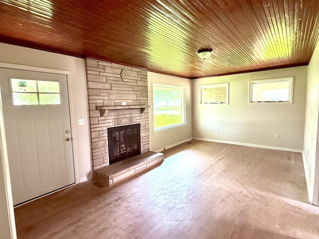 unfurnished living room featuring wood ceiling, a stone fireplace, wood finished floors, baseboards, and ornamental molding