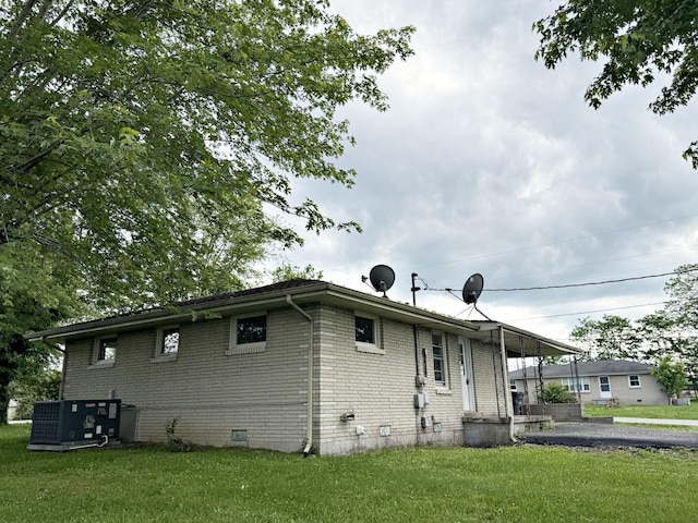 rear view of house featuring brick siding, a yard, crawl space, and central AC