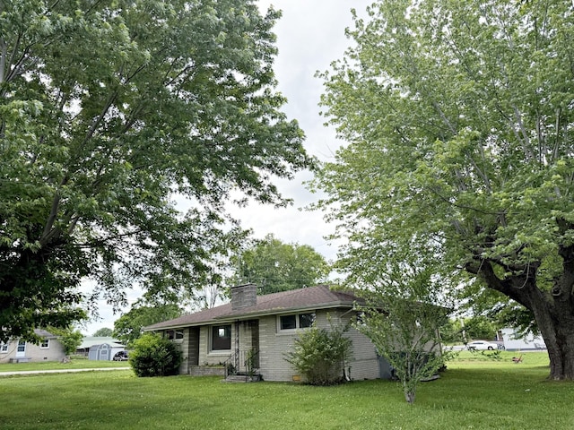 single story home featuring a front lawn, a chimney, and brick siding