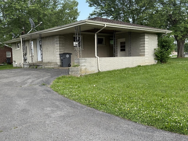 view of front of home featuring brick siding, a front yard, and driveway