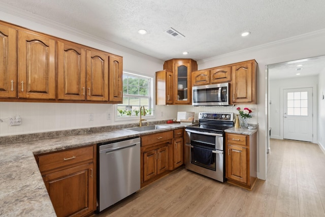 4588 Roy Thompson Rd, Mount Pleasant, TN 38474 - kitchen with appliances with stainless steel finishes, a sink, brown cabinetry, light wood-style flooring, and ornamental molding