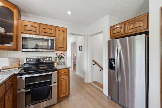 4588 Roy Thompson Rd, Mount Pleasant, TN 38474 - kitchen featuring stainless steel appliances, brown cabinetry, light wood-type flooring, crown molding, and glass insert cabinets