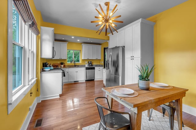 2642 Stuart St, Burns, TN 37029 - kitchen with stainless steel appliances, a sink, baseboards, white cabinetry, and light wood-style flooring