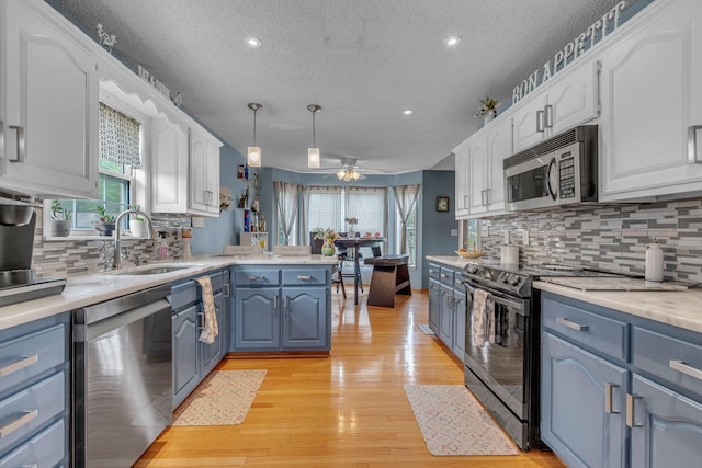 1383 Carters Creek Pike, Columbia, TN 38401 - kitchen featuring appliances with stainless steel finishes, a peninsula, a sink, a textured ceiling, and blue cabinets