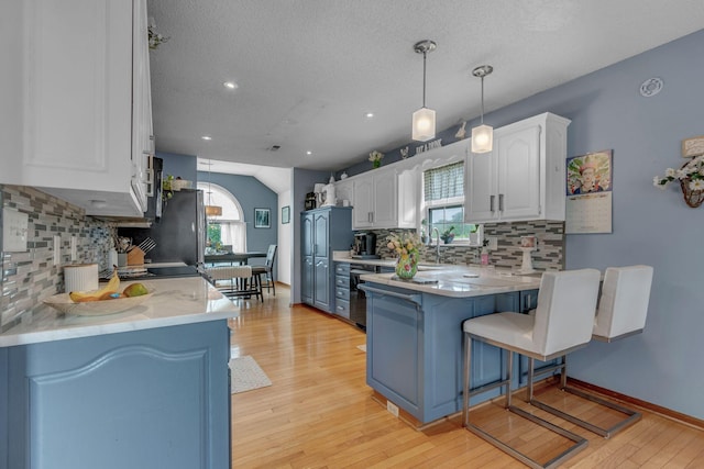 1383 Carters Creek Pike, Columbia, TN 38401 - kitchen featuring a peninsula, tasteful backsplash, white cabinets, a kitchen bar, and light wood-style flooring