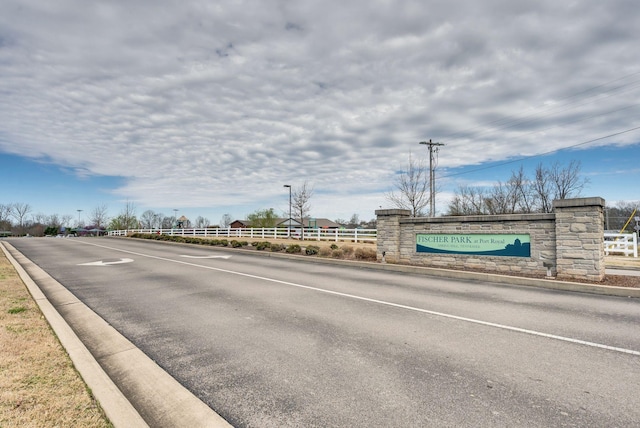 view of asphalt street featuring curbs and street lights