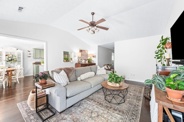 living area with vaulted ceiling, ceiling fan, dark wood-type flooring, and baseboards