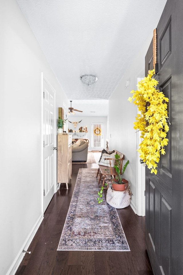 foyer with dark wood finished floors, baseboards, and a ceiling fan
